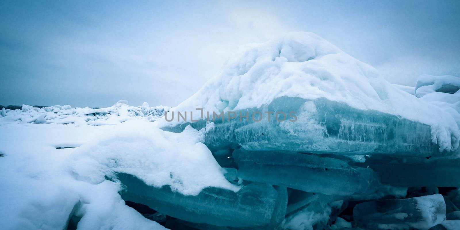 Stunning view of the frozen river covered with chunks of ice and white frosted snow. Snowy desert. The river breaks through the ice.