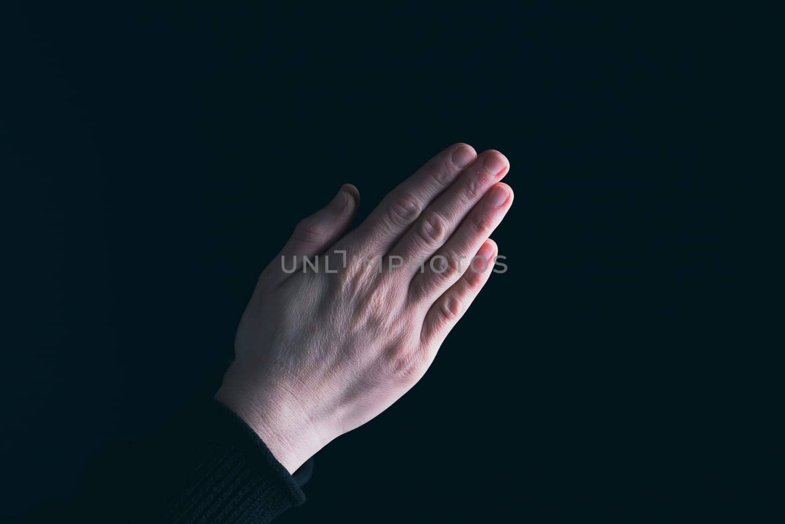 Praying hands with faith in religion and belief in God on dark background. Power of hope or love and devotion.