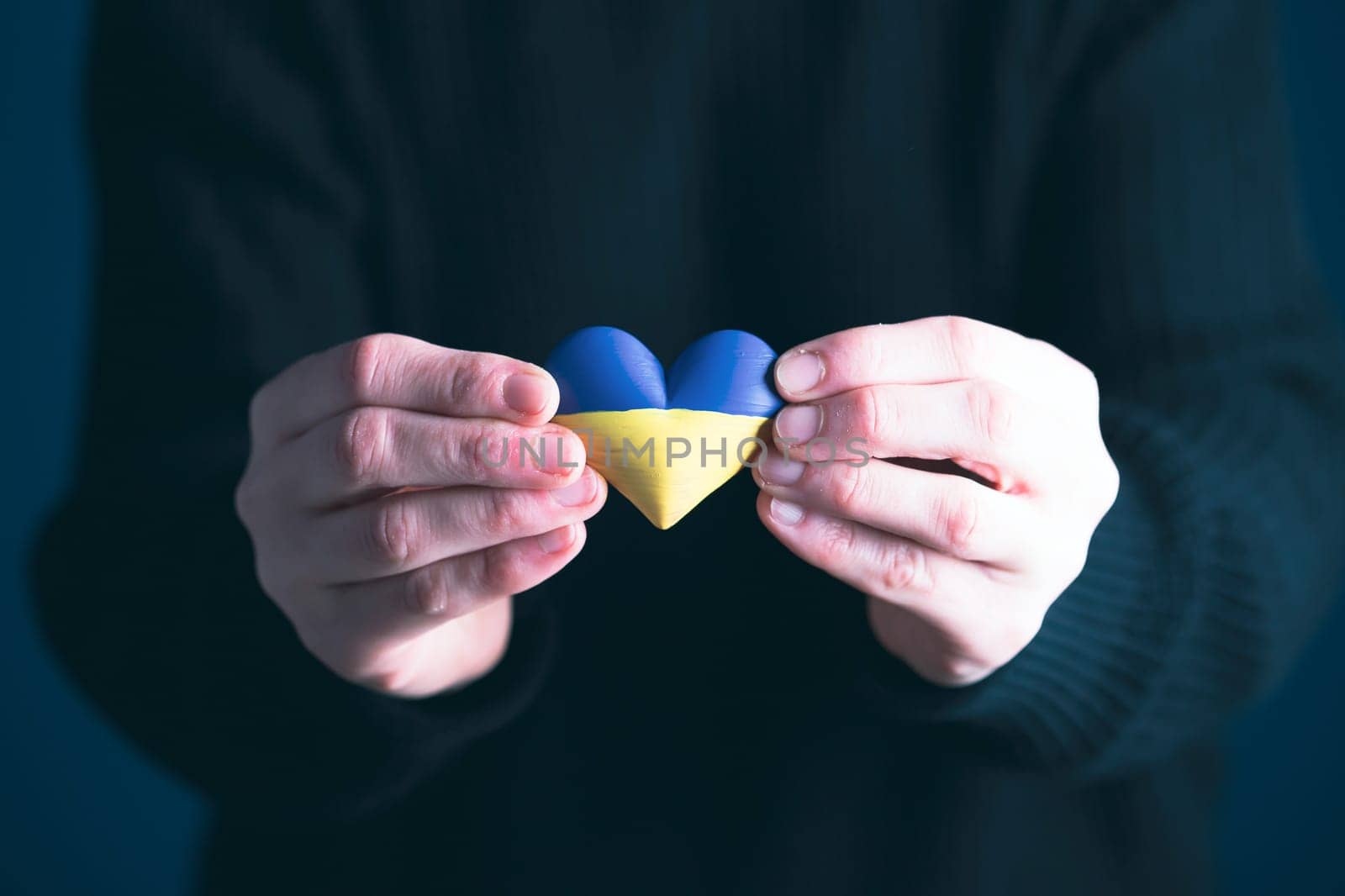 Heart shaped flag of Ukraine in female hands. The concept of solidarity with the citizens of Ukraine.