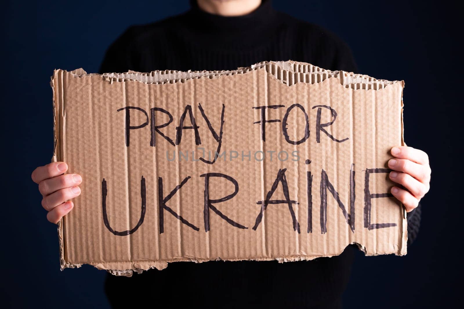 Woman holds a banner with anti-war message. Protest against the Russian intervention to Ukraine, activism and human rights movement. Concept of standing with Ukrainian.