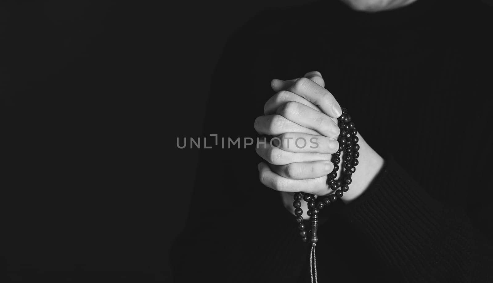 Religious young woman praying to God, on dark background.