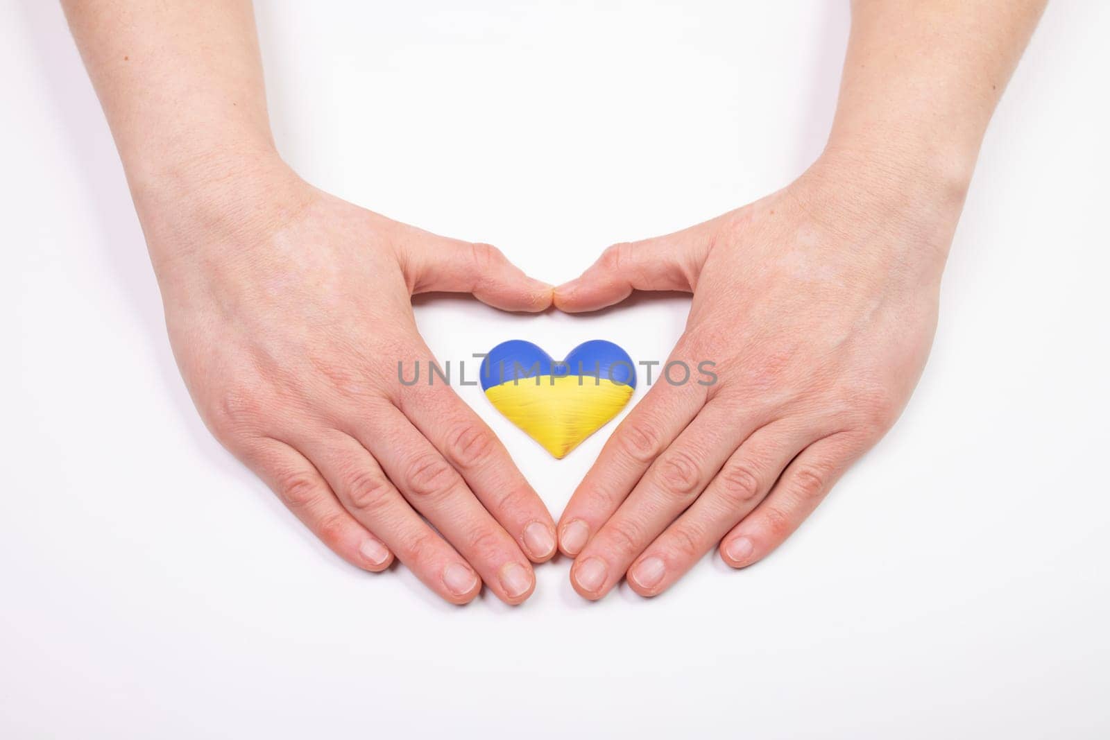 Heart shaped flag of Ukraine in female hands. The concept of solidarity with the citizens of Ukraine.