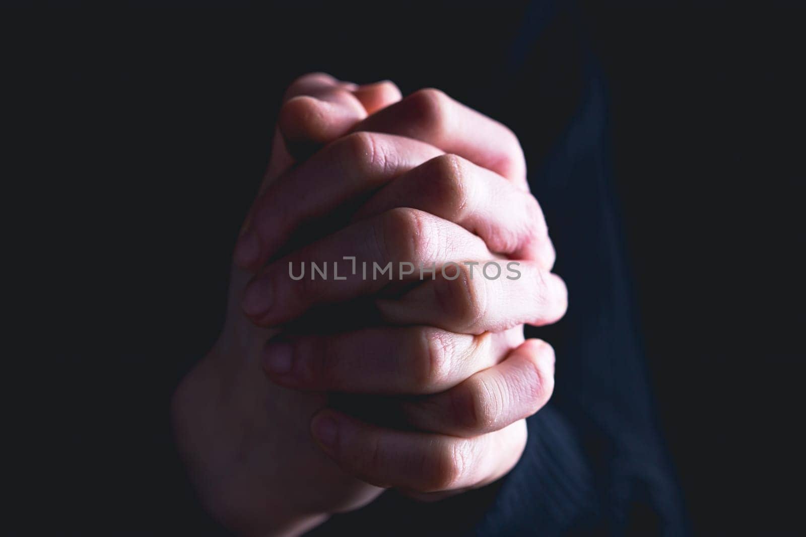 Praying hands with faith in religion and belief in God on dark background. Power of hope or love and devotion.