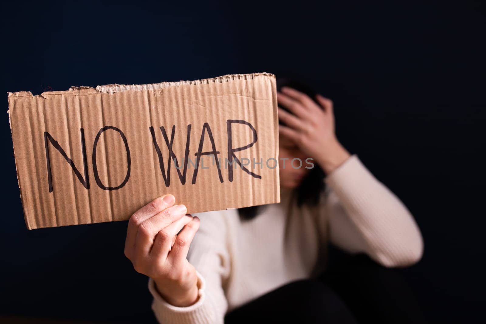 Sad woman calls to Stop war in Ukraine, raises banner with inscription No war.