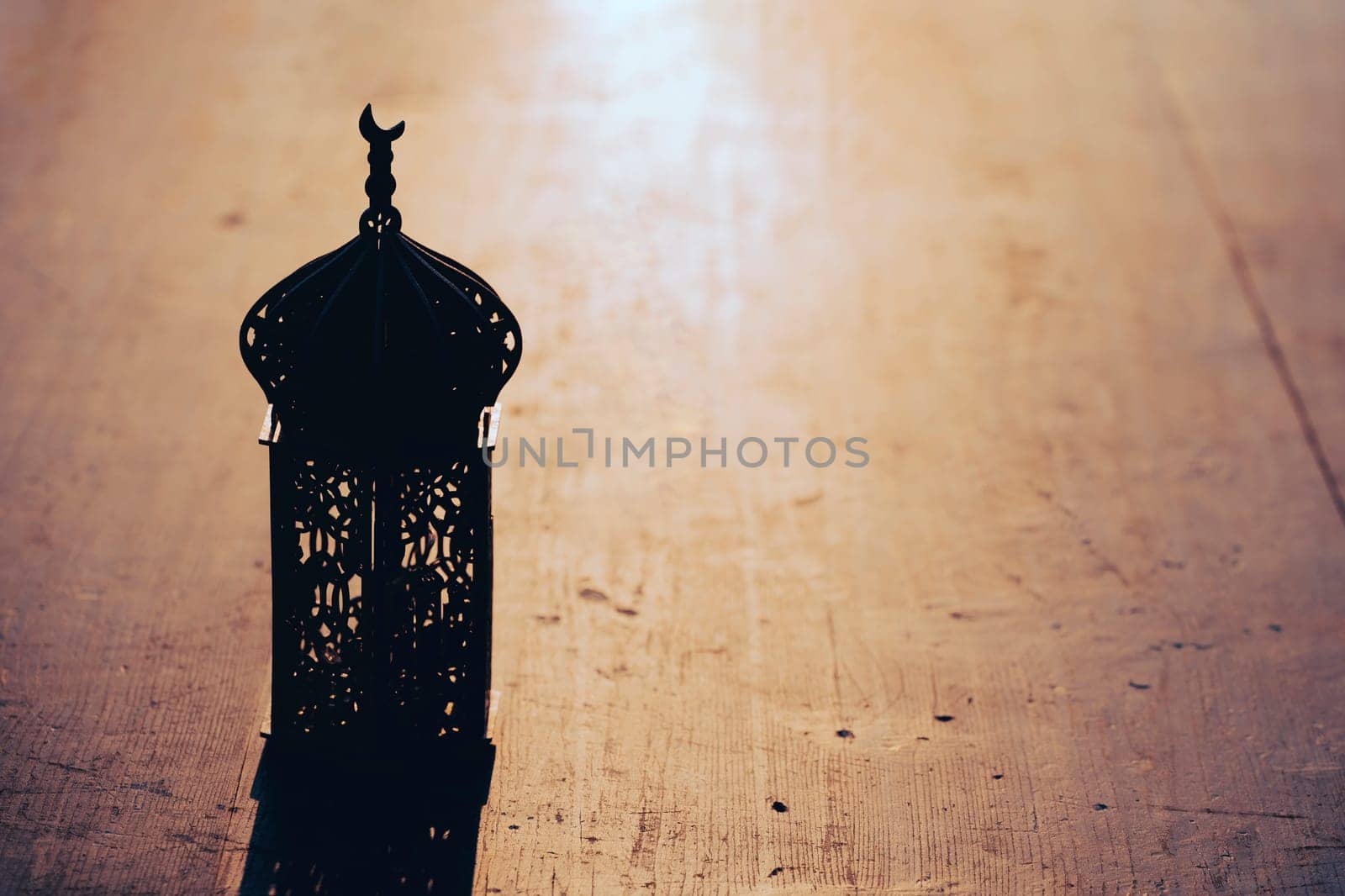 Ramadan Kareem background. Ornamental Arabic lantern on vintage wooden background in the sunset