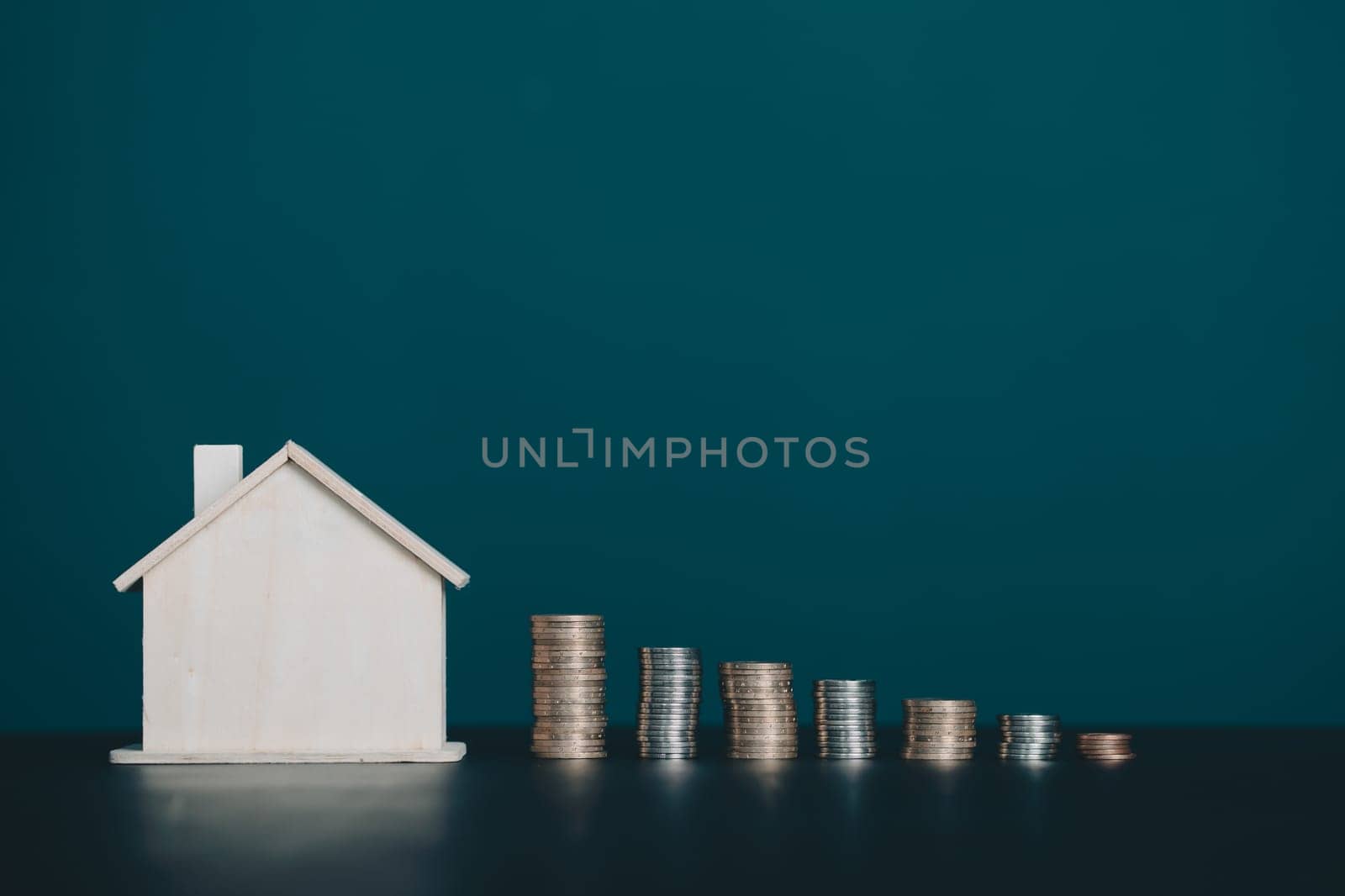 Coin stack with house model on table with copy space. Realtor, mortgage, your house, home loan concept.