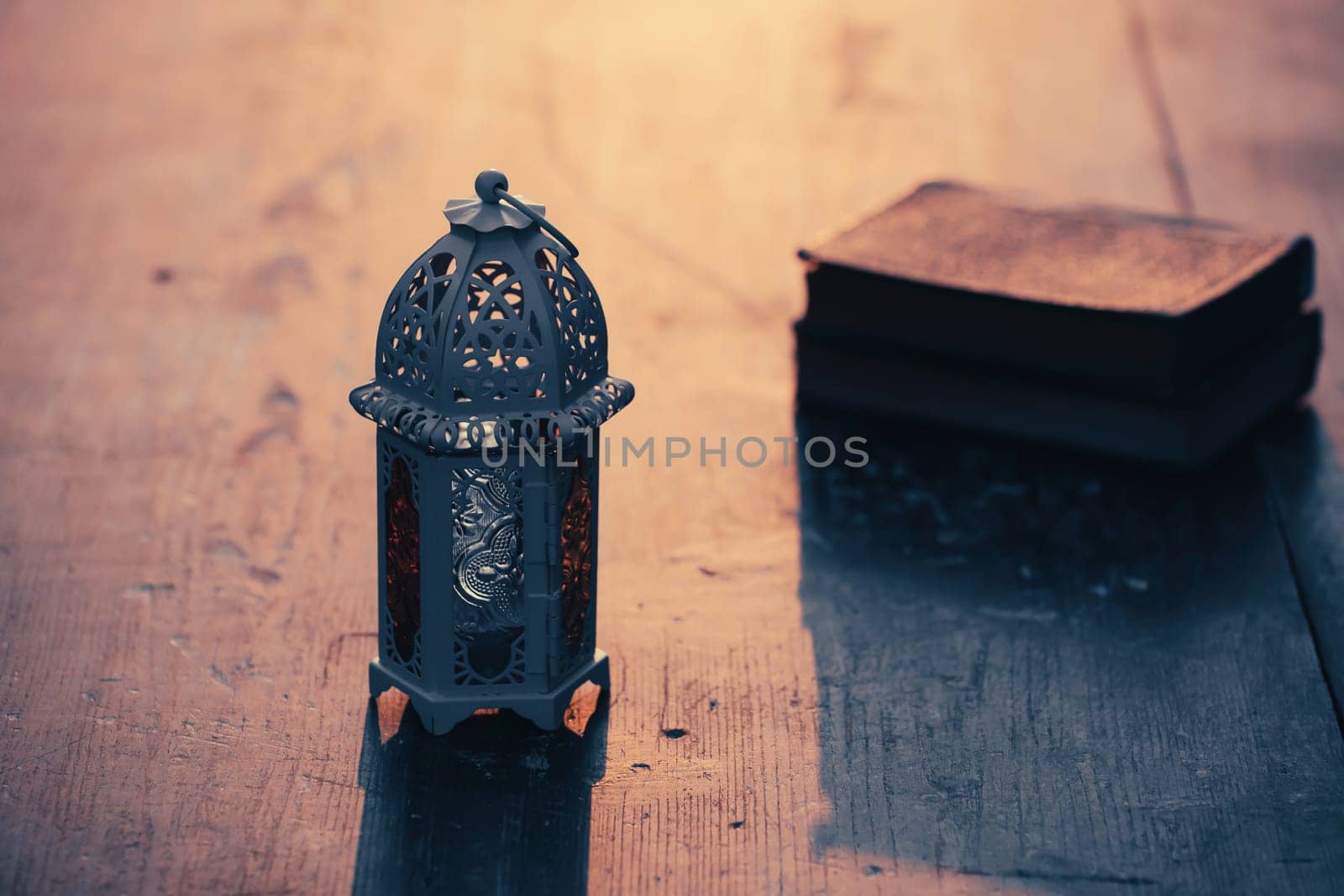 Ramadan Kareem background. Ornamental Arabic lantern glowing at night and the holy book of Quran.