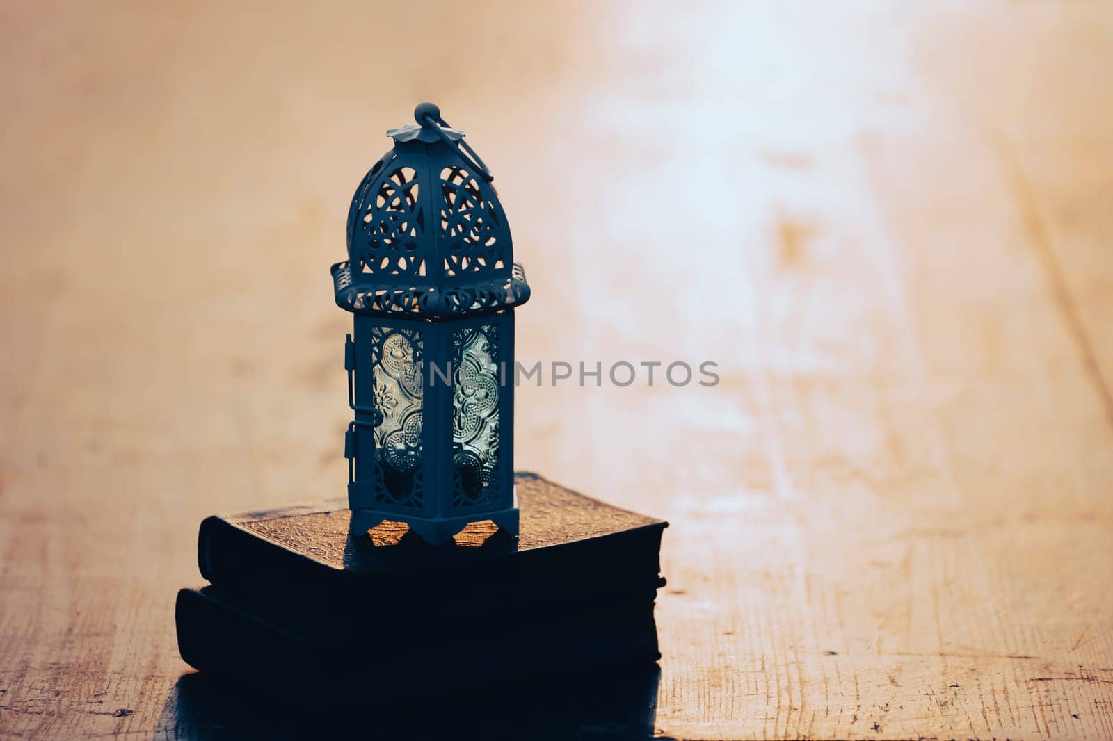Ramadan Kareem background. Ornamental Arabic lantern glowing at night and the holy book of Quran.