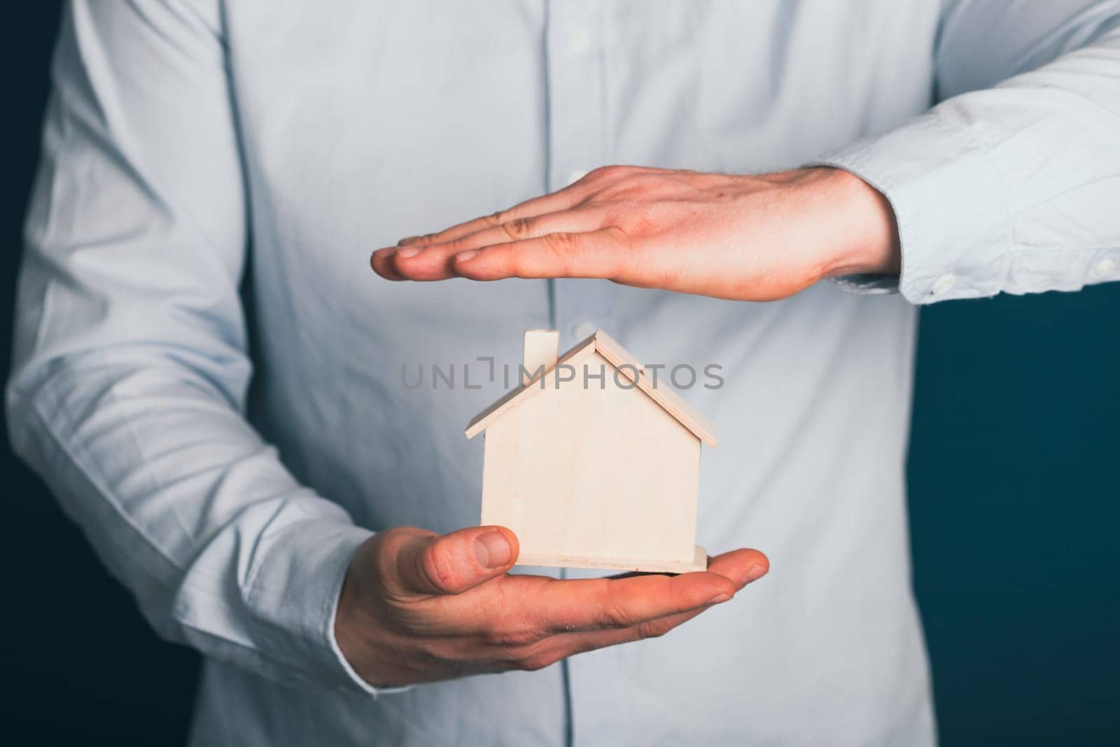 Real estate agent protecting house model. Property insurance and security concept.