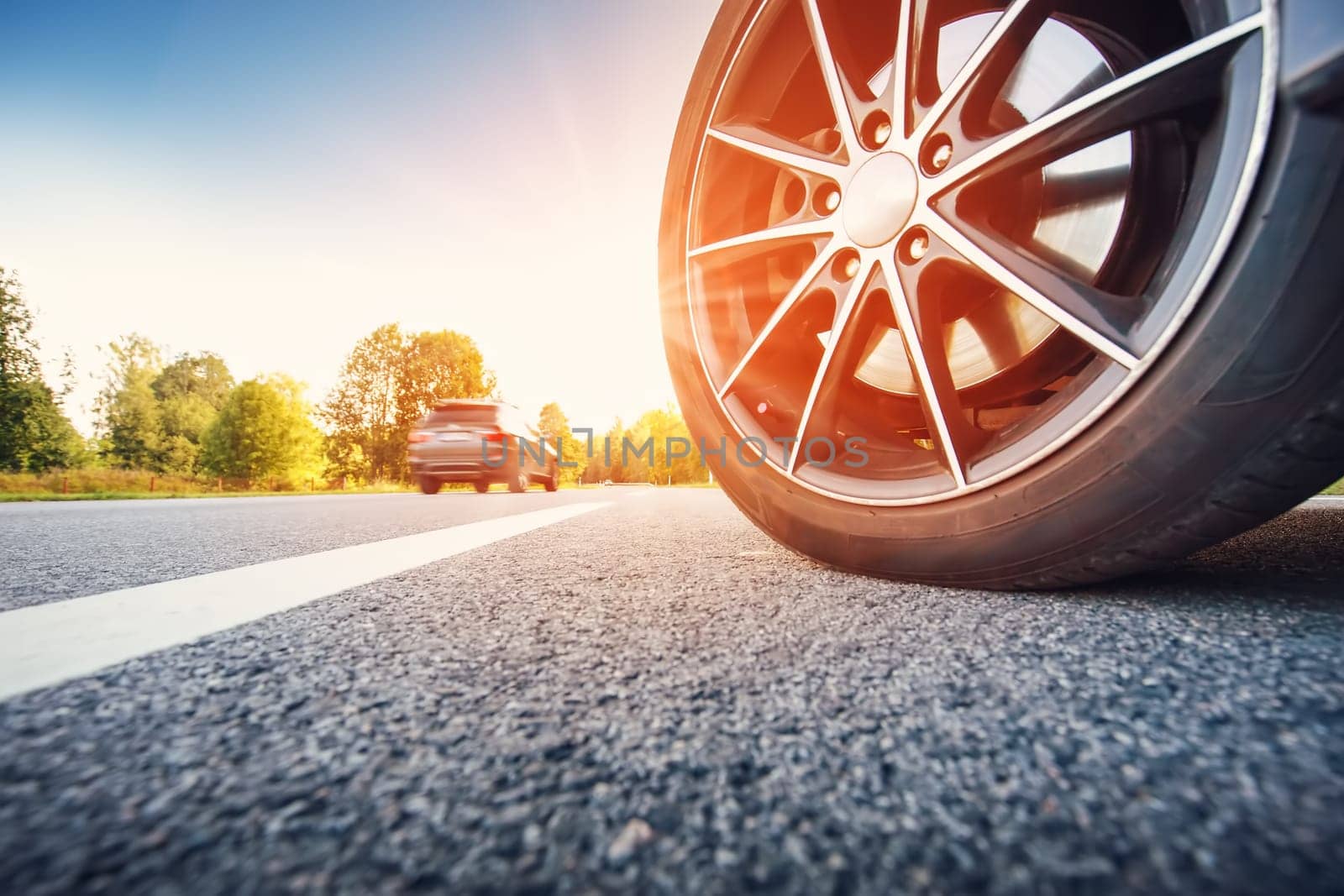 Close-up view of the car's wheel on the highway. Beautiful view of the natural background.