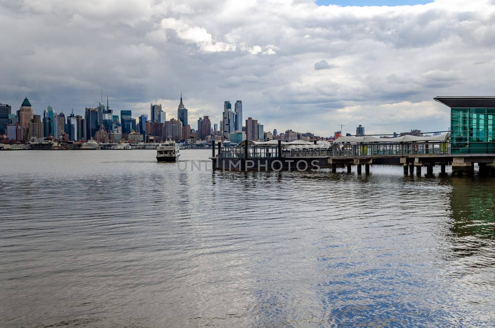 Port Imperial / Weehawken Ferry Terminal at Hudson River, New Jersey with Ferry, side view during cloudy winter day, horizontal