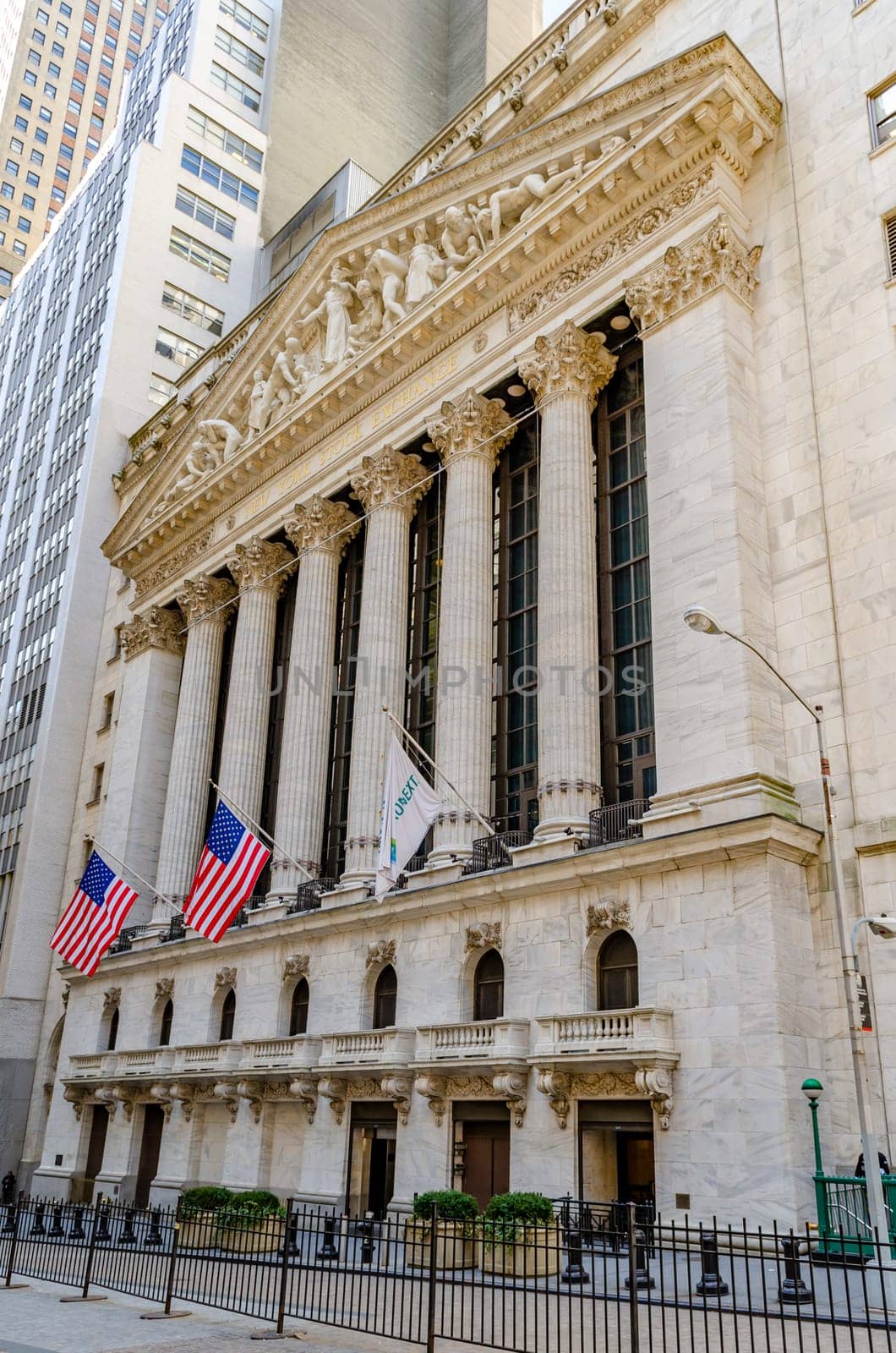 New York Stock Exchange Building with columns and American flag hanging down in front, low angle view during winter, vertical