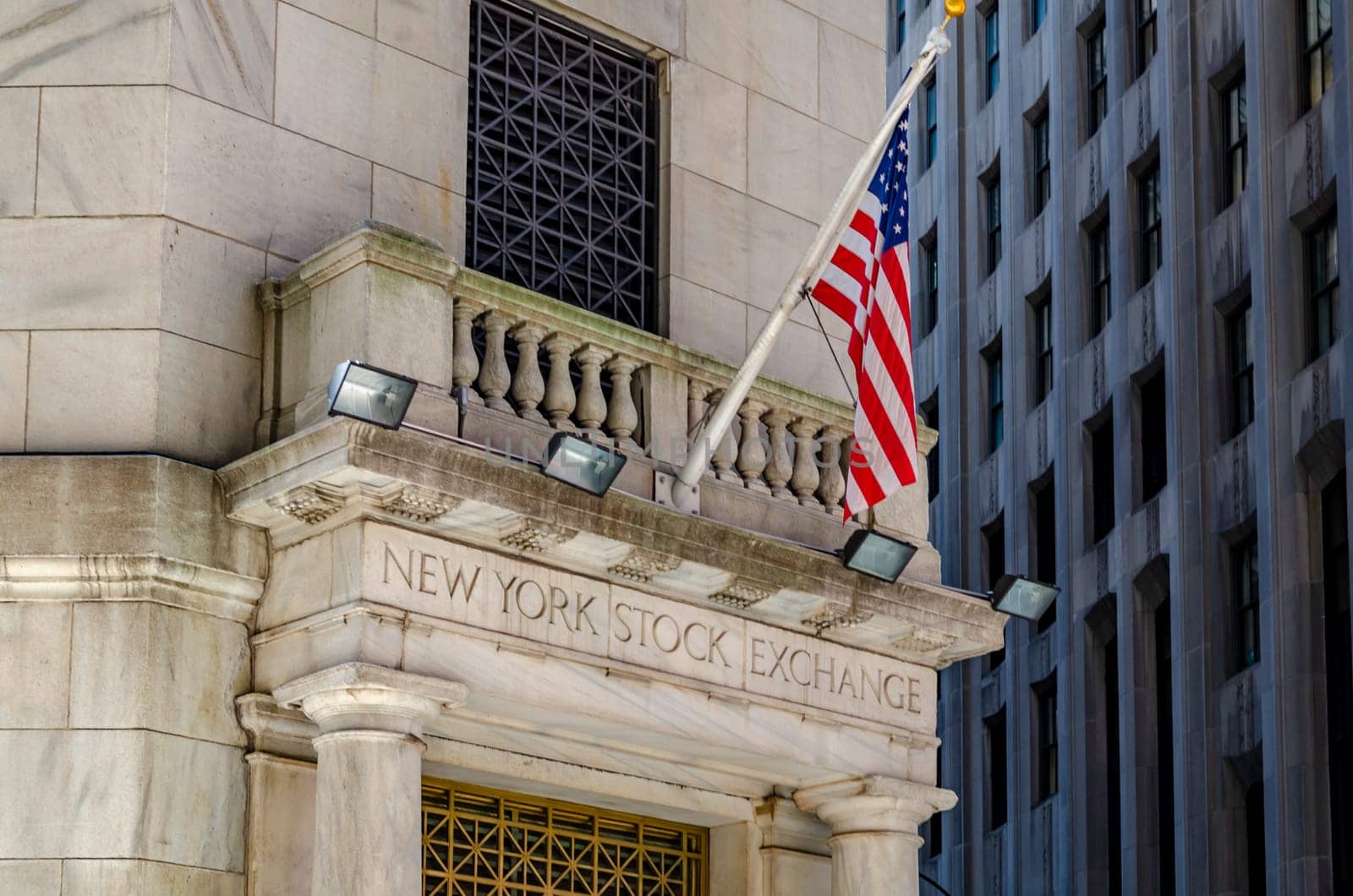 New York Stock Building Exchange golden colored Building Entrance, close-up with American Flag above during winter, vertical