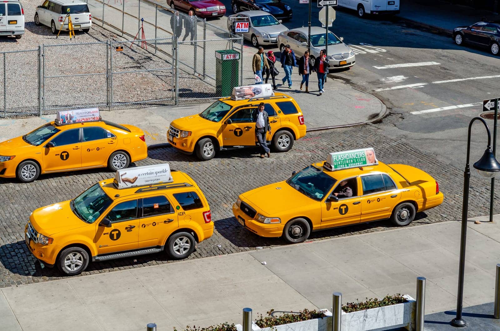 Different car models of Yellow taxi cabs parked in side street in Chelsea, New York City during sunny winter day, horizontal