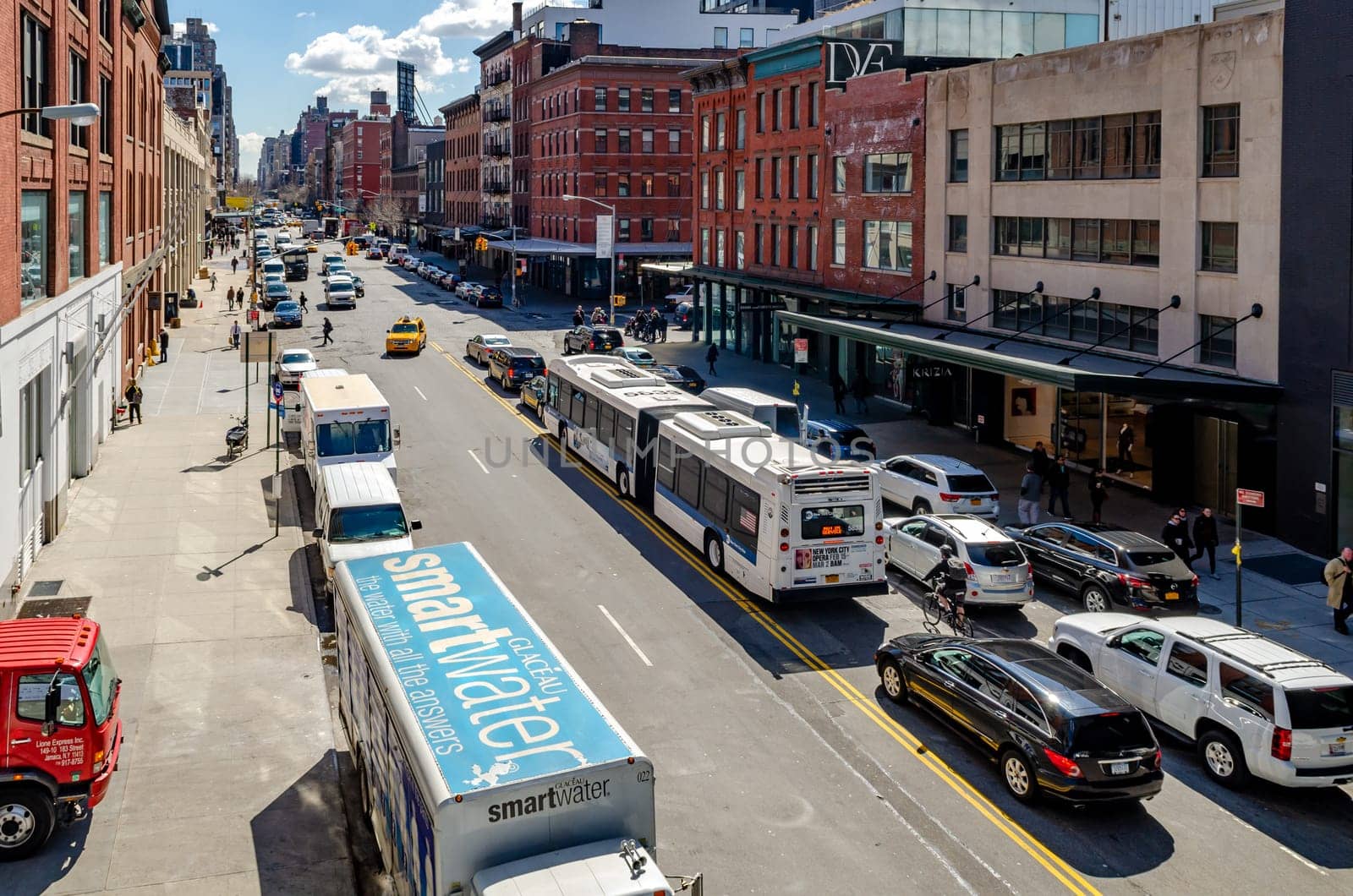 Chelsea city Street with cars parked next to the street and traffic, bus passing by, New York City, view from the High Line Rooftop Park, New York City during sunny winter day, horizontal