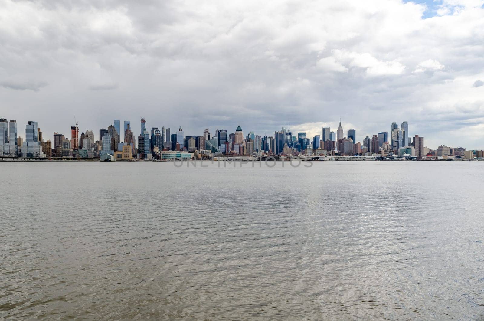 Wide angle shot of New York City Manhattan Skyline with Empire State Building and Hudson river in front during cloudy winter day, horizontal