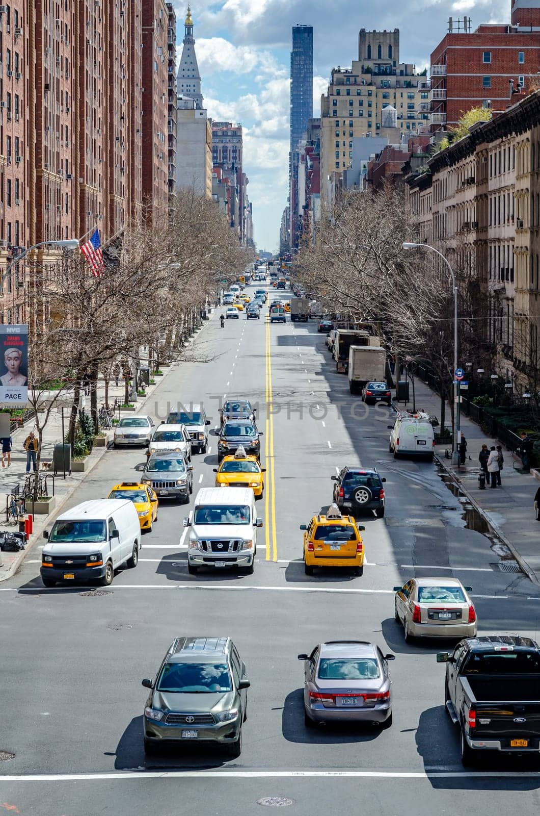 Chelsea City Street with traffic passing by, aerial view from the High Line Rooftop Park, New York City during sunny winter day, Building facades surround the street, vertical