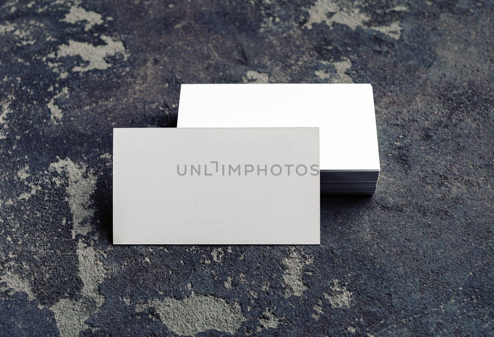 Photo of blank business cards on concrete background. For design presentations and portfolios. Mock-up for branding identity.