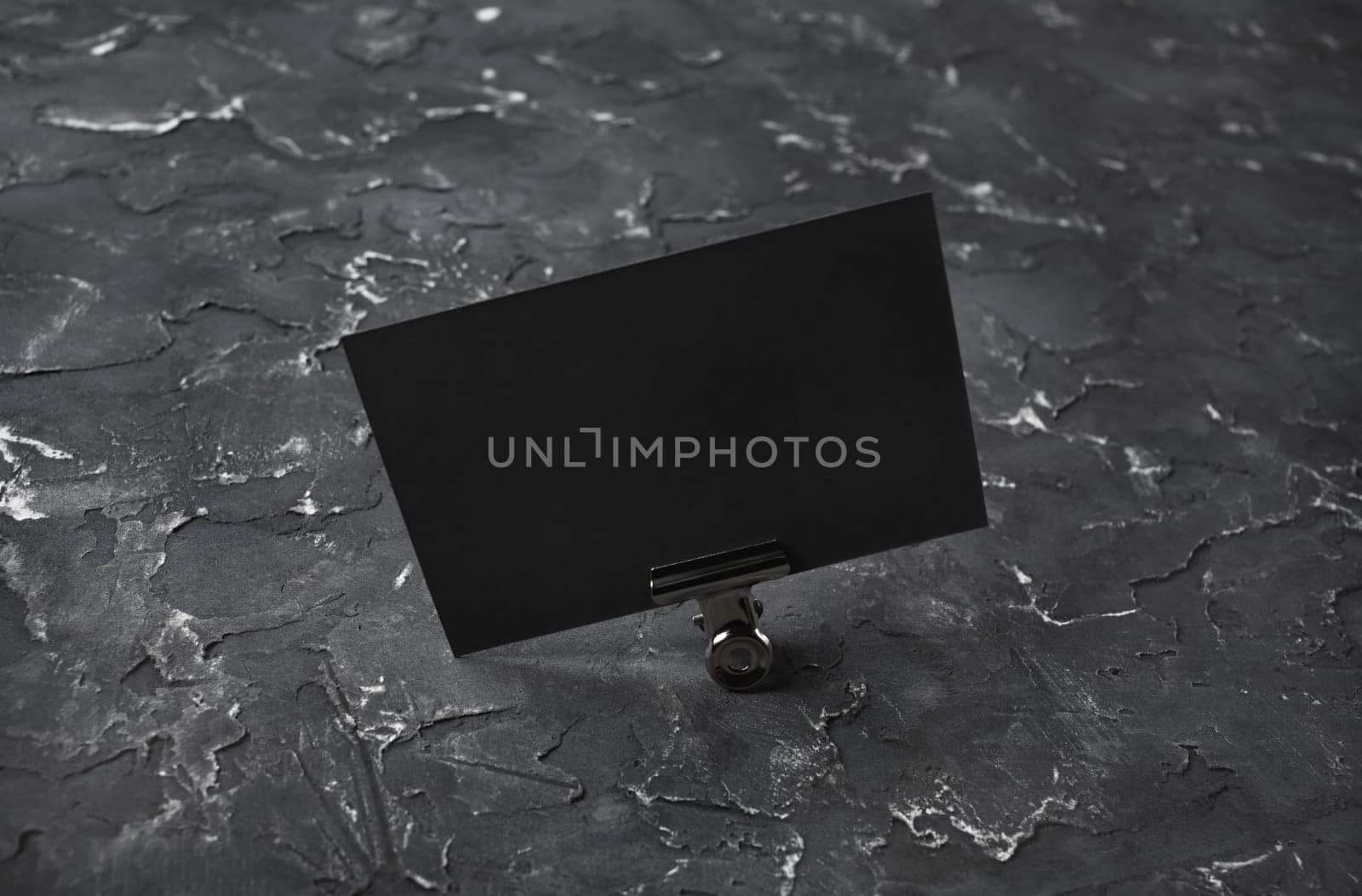 Photo of blank black business card on black plaster background. Mock-up for branding identity.