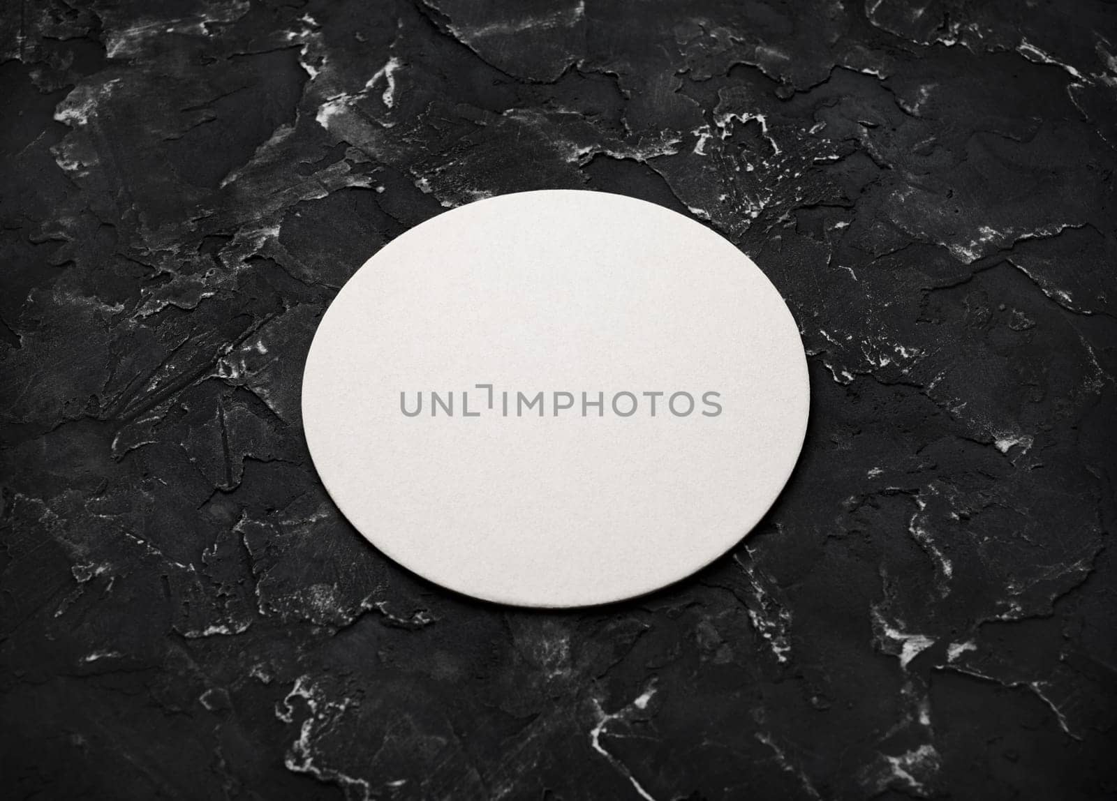 Blank white beer coaster on black plaster background. Responsive design mockup.