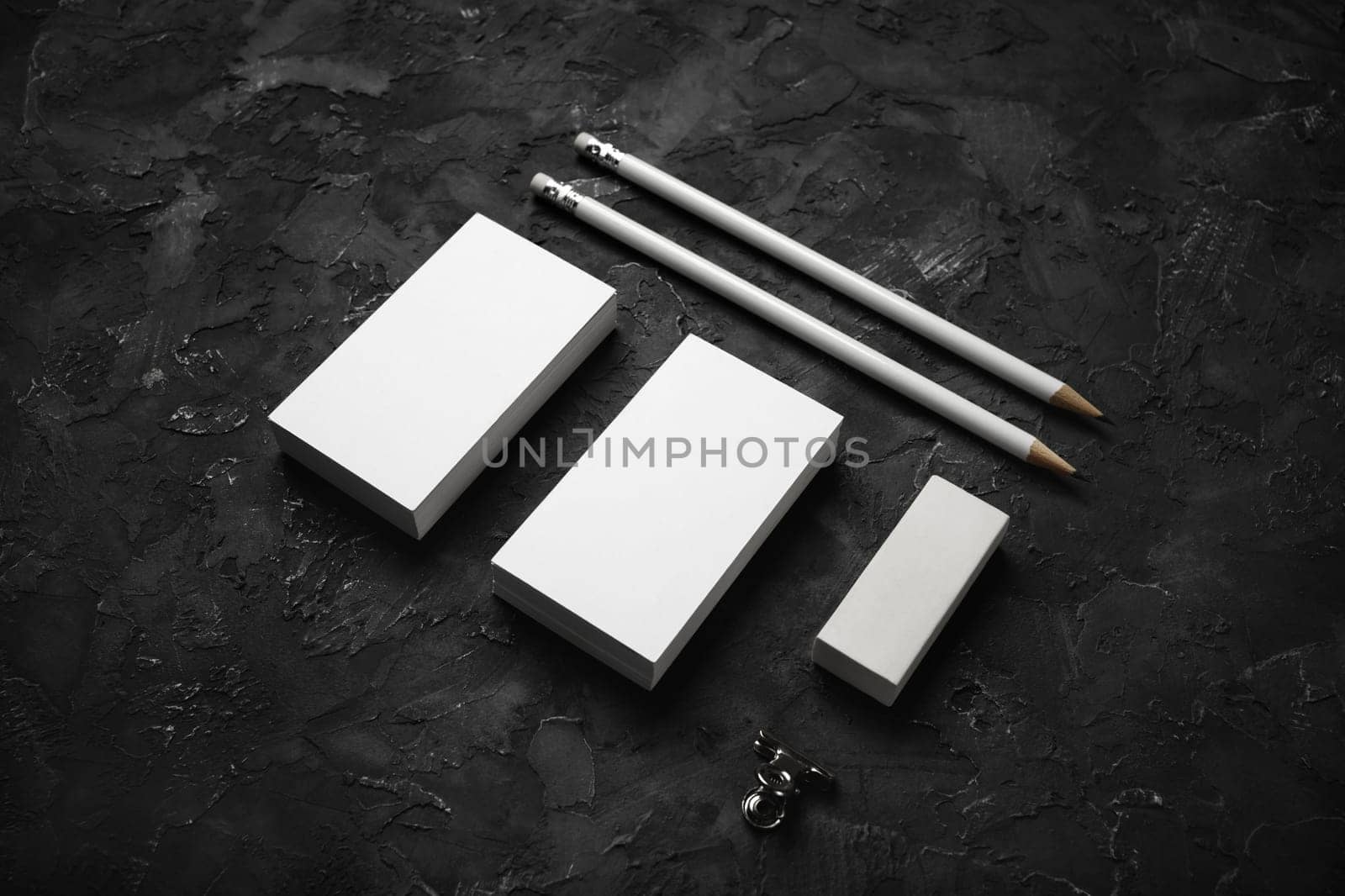 Blank business cards, pencils and eraser on black plaster background. Stationery mockup. Objects for placing your design.