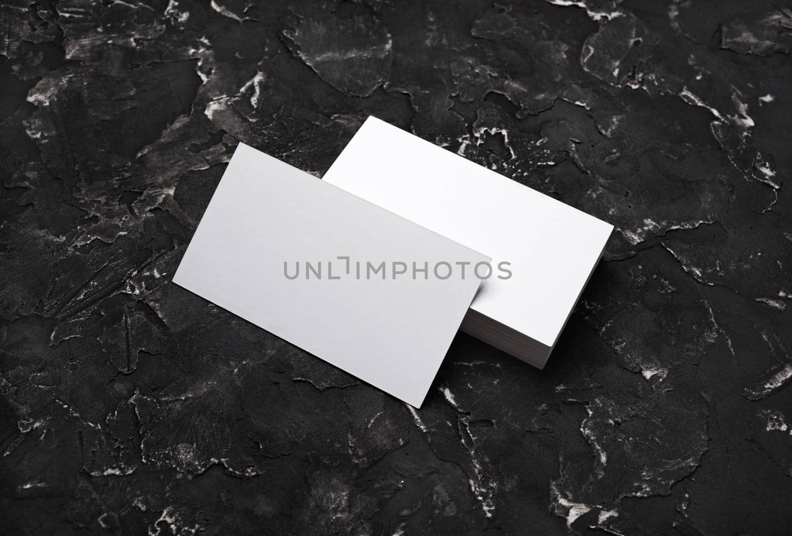 Blank white business cards on black plaster background. Mockup for branding identity. Template for graphic designers portfolios.