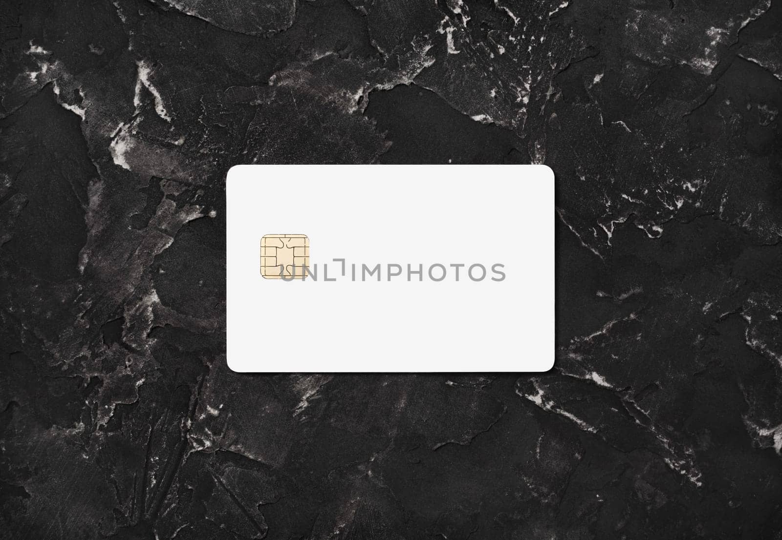 Blank white credit card on black plaster background. Bank card. Top view. Flat lay.
