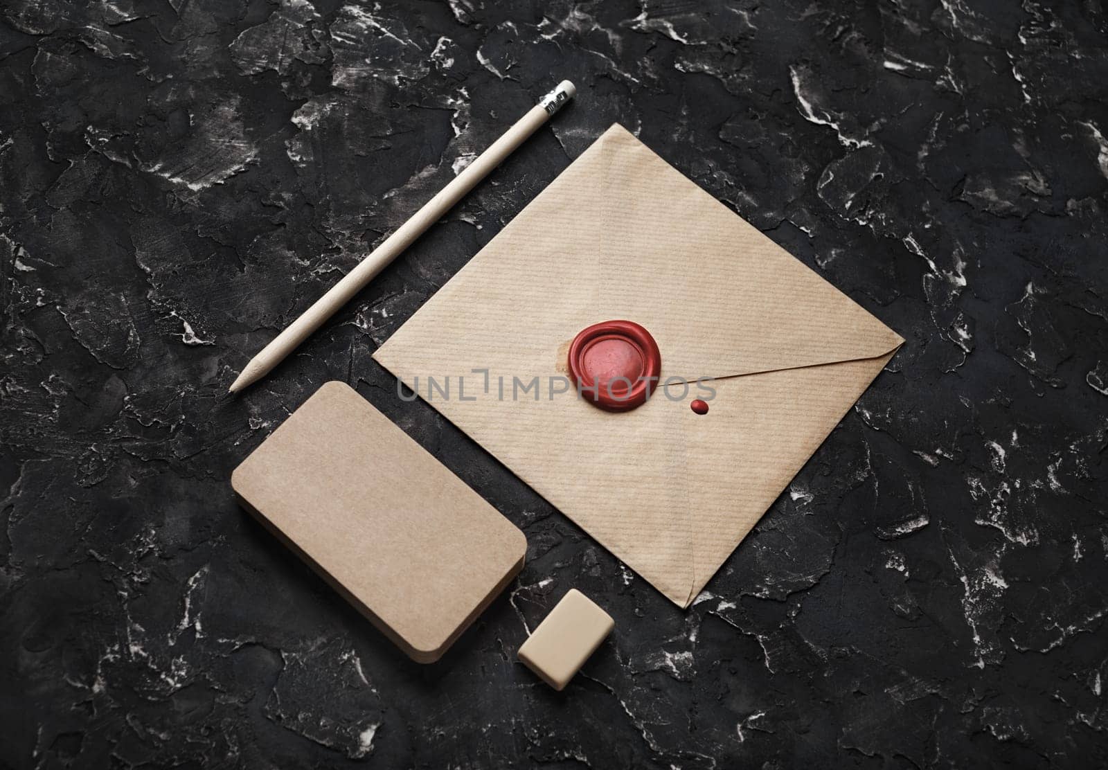 Photo of blank vintage envelope and stationery on black plaster background.