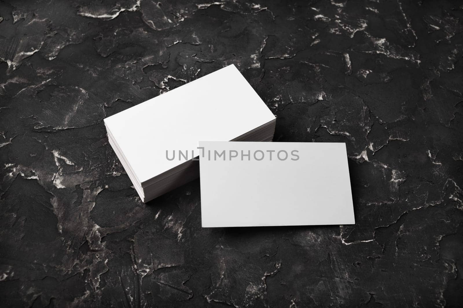 Blank white business cards on black plaster background. Mockup for branding identity.