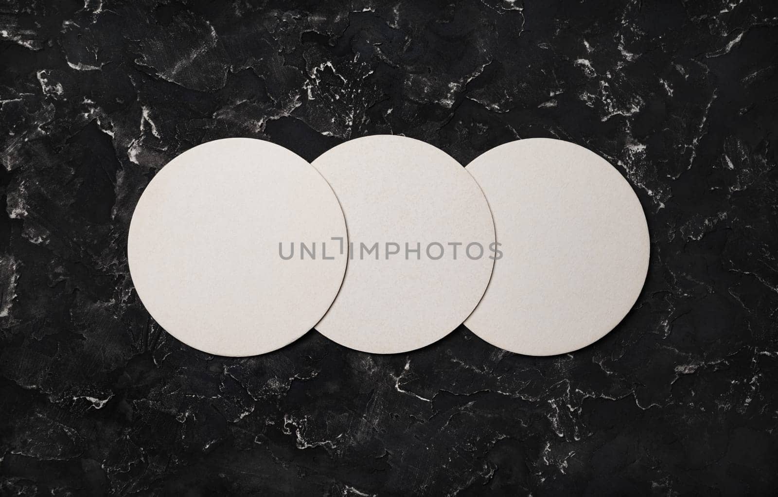 Three blank beer coasters on black plaster background. Responsive design mockup. Top view with copy space. Flat lay.