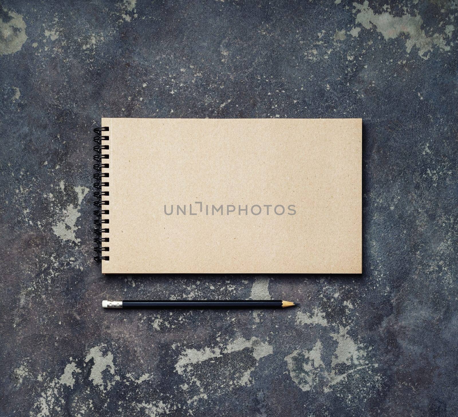 Photo of blank vintage sketchbook and pencil on concrete background. Copy space for text. Top view. Flat lay.