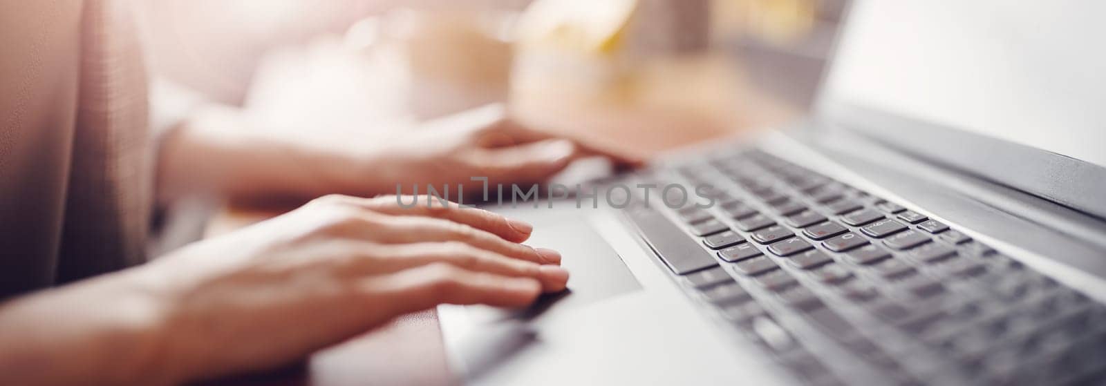 Woman with smartphone in her hand working on the laptop in office. Place of work. Close-up view.