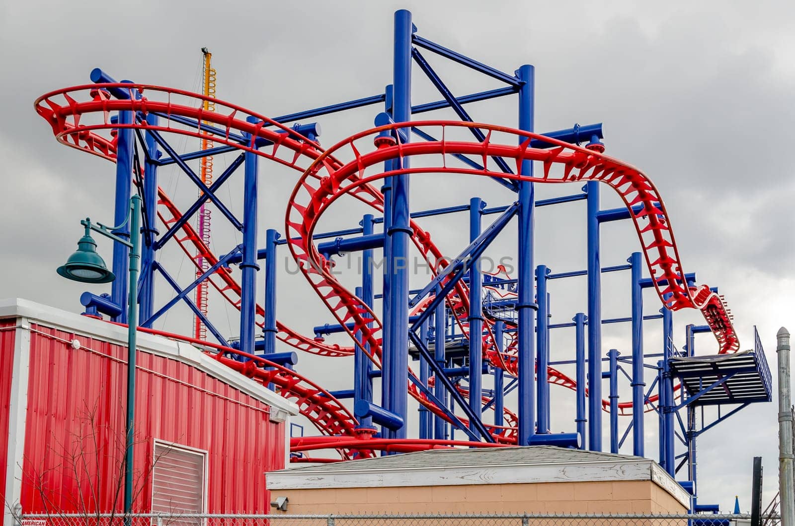 Soarin' Eagle Rollercoaster at Coney island, Brooklyn, New York City during winter day with cloudy sky, view from low angle, buildings in front, horizontal