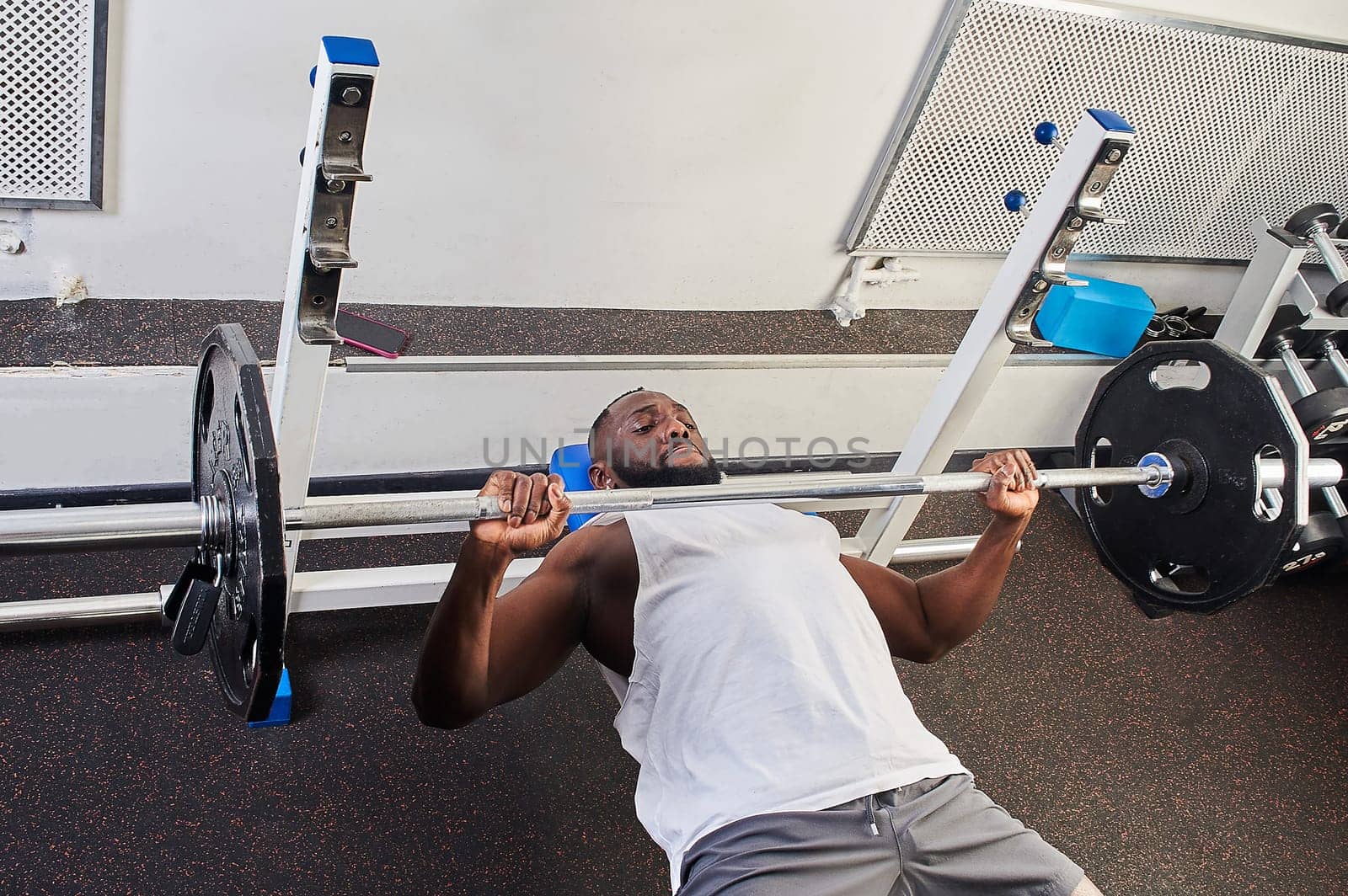 An African American man does a bench press lying on a bench in the gym. High quality photo