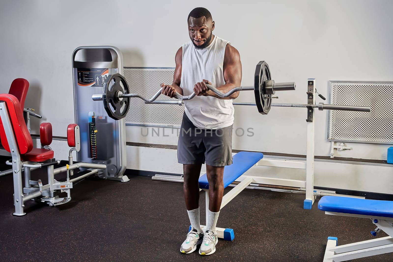 African-American man shakes biceps in the gym. High quality photo