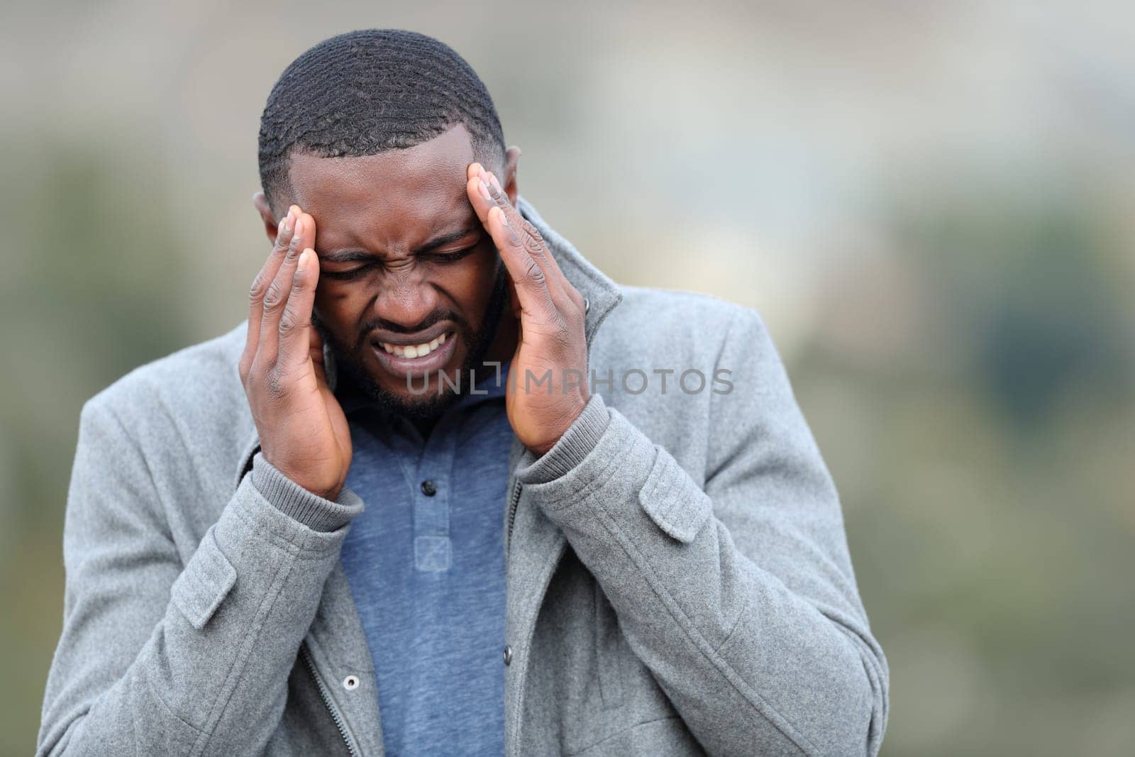 Stressed man with black skin suffering migraine in winter