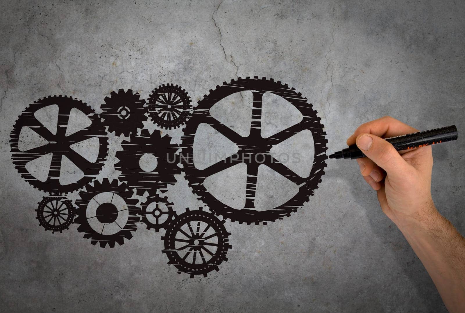 Hand drawing black gears on gray wall