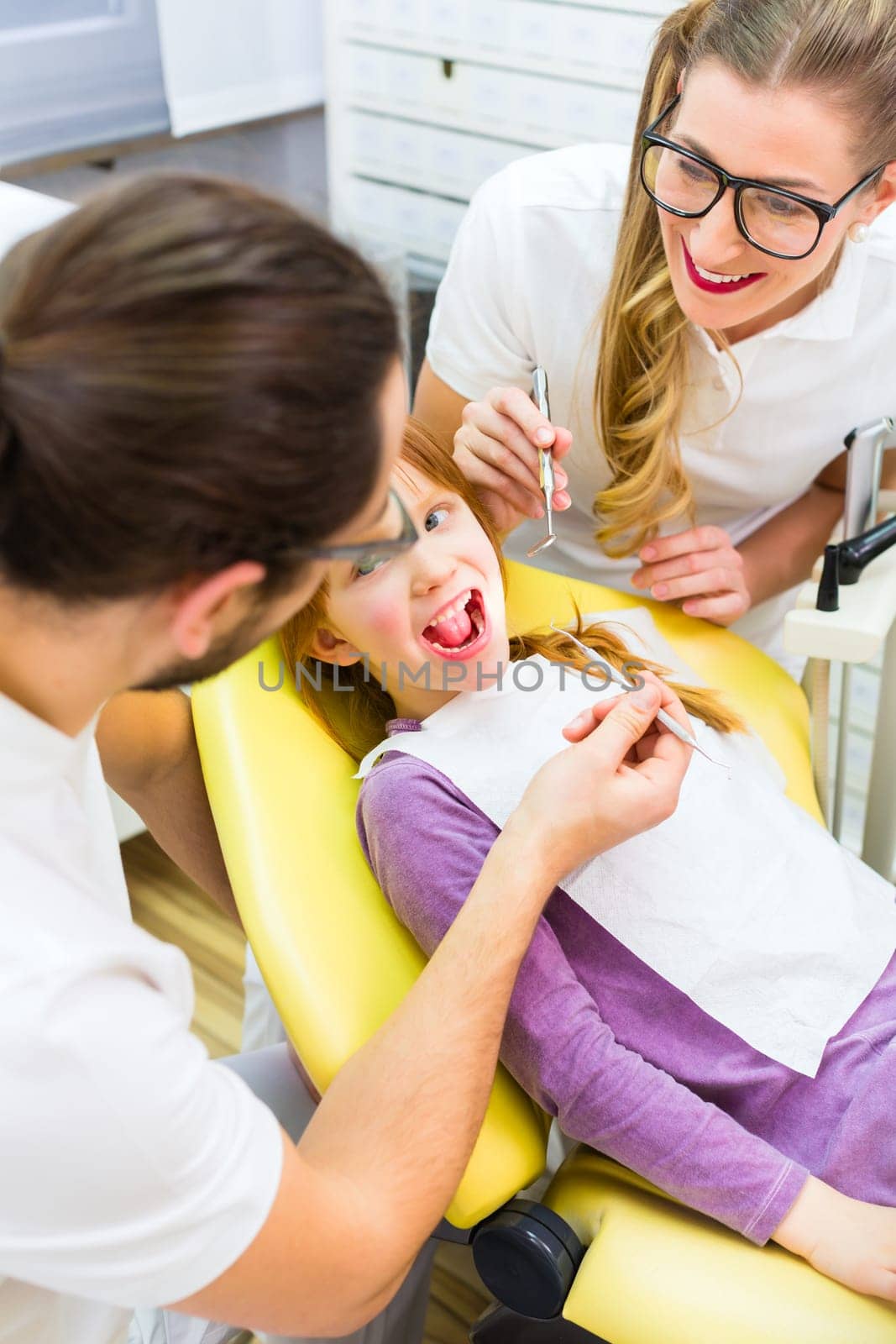 Dentist and assistant treat patient in dental practice