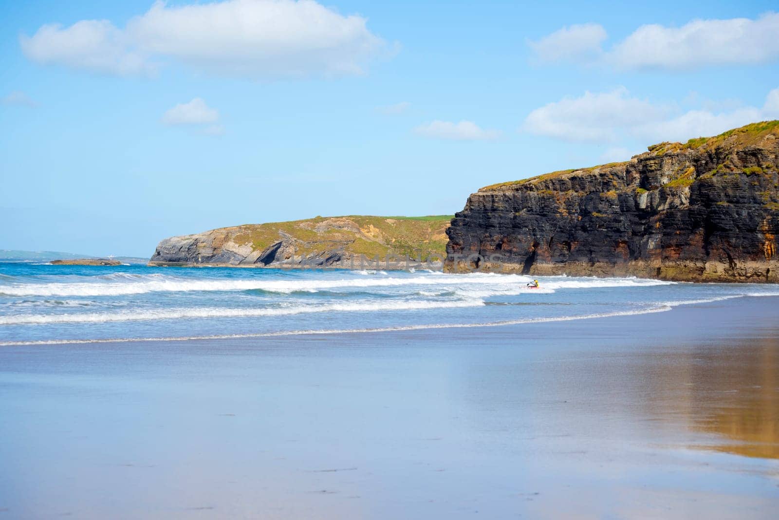 bright winter view of kayaker at ballybunion beach and cliffs on the wild atlantic way in ireland