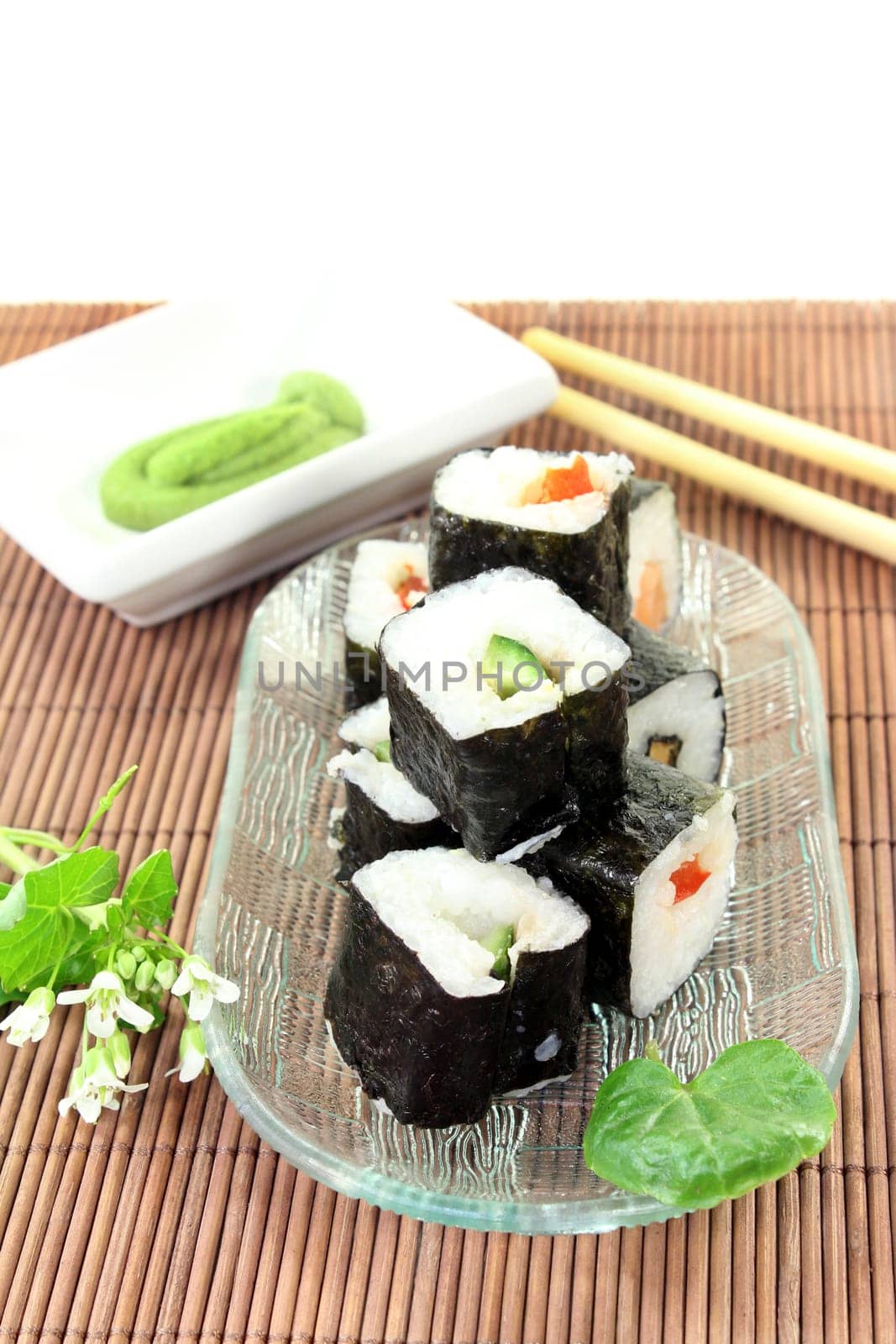 a glass bowl with sushi and fresh wasabi leaves