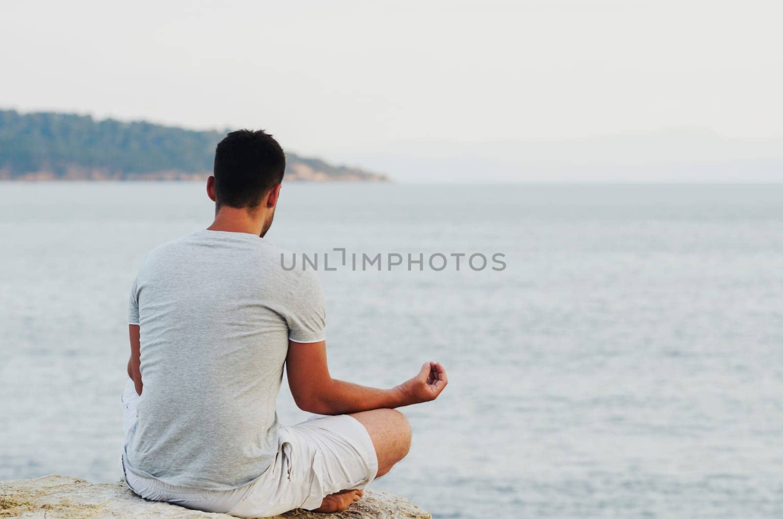 Young man sitting on the coast and meditating