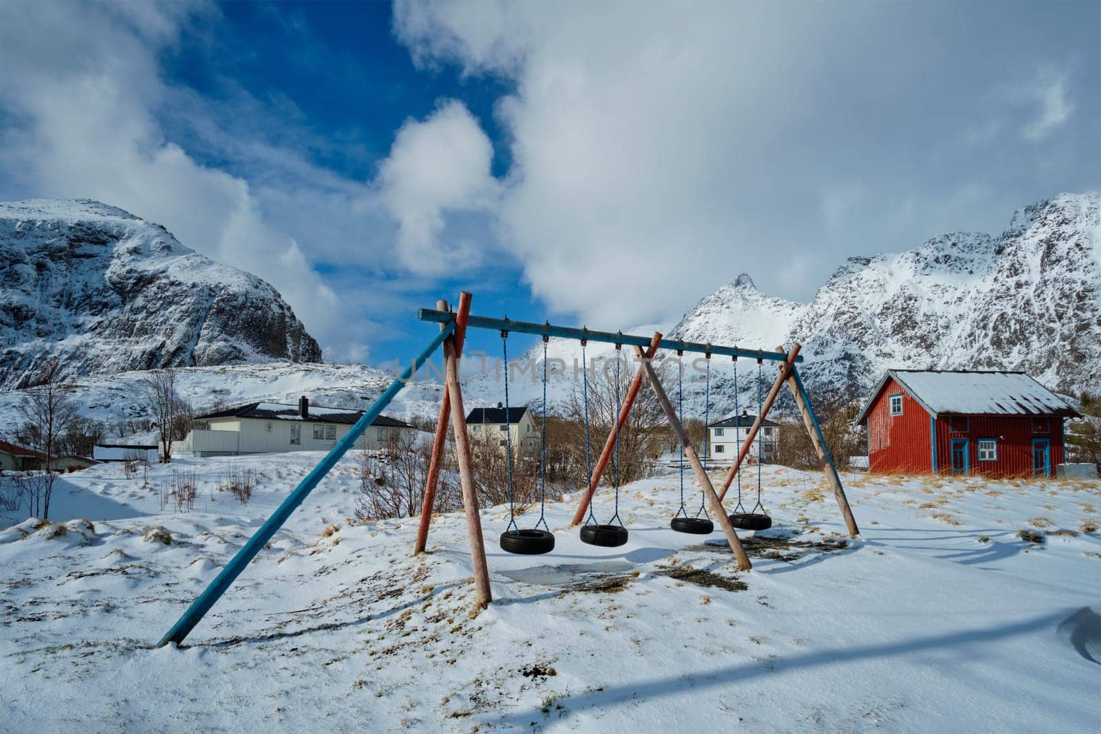 Children playground with swings made of car tires in winter. A village, Lofoten islands, Norway