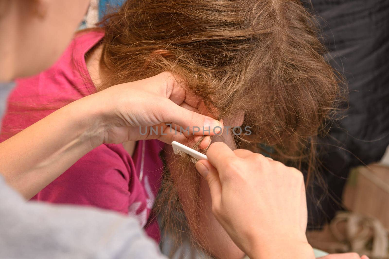 Mom tries to comb the girl's heavily tangled hair, close-up