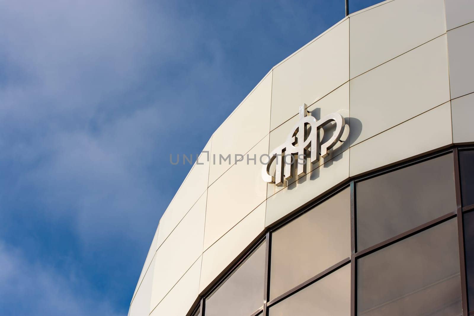 Anapa, Russia - November 6, 2021: The logo of the Pension Fund of the Russian Federation on the facade of the building, in the background there is a blue sky with small clouds