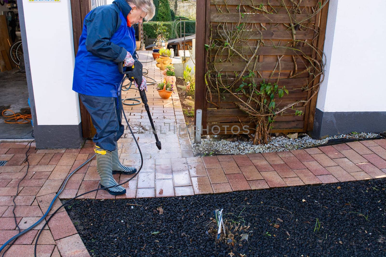 Worker cleaning driveway with gasoline high pressure washer splashing the dirt,professional cleaning services.High pressure cleaning,lower body.