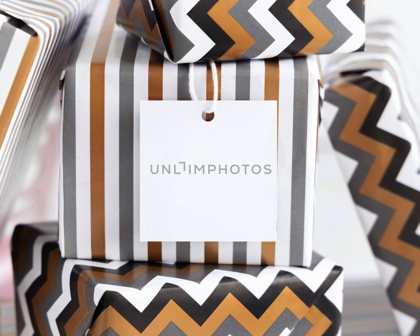 Present with blank square gift tag close up. Gift boxes wrapped in Striped and chevron geometric paper. Christmas, New Year, Birthday, Anniversary label mockup