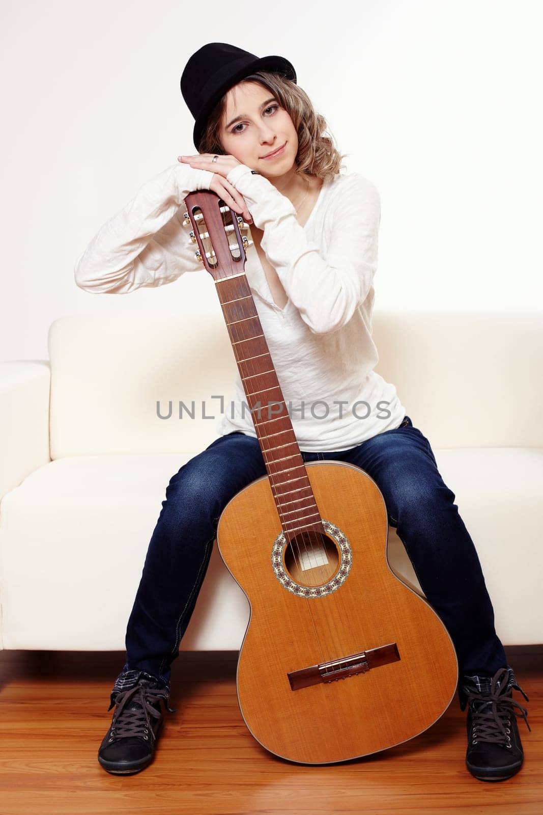 Young woman with a guitar sitting on a sofa