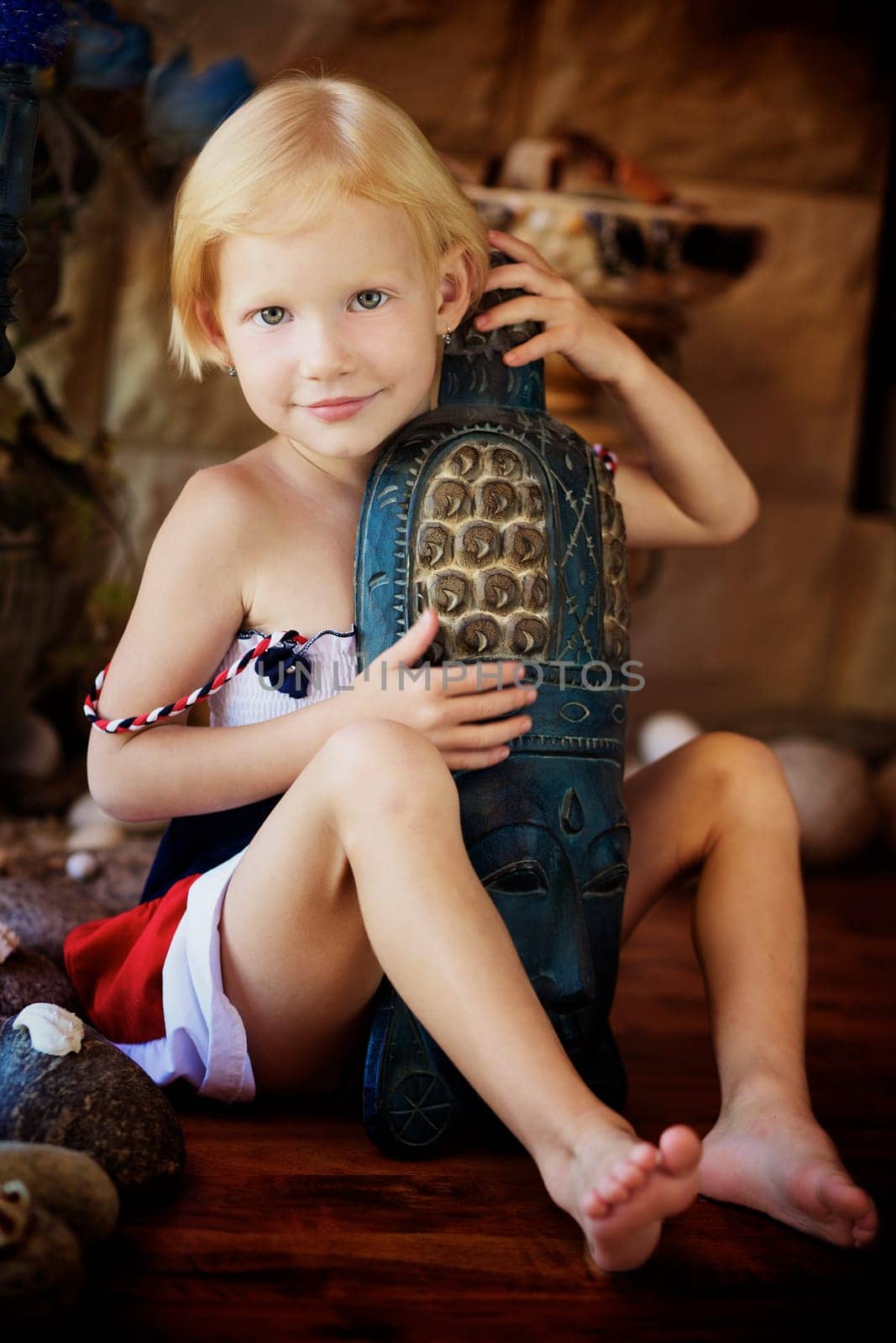 Portrait of a little girl holding an african mask