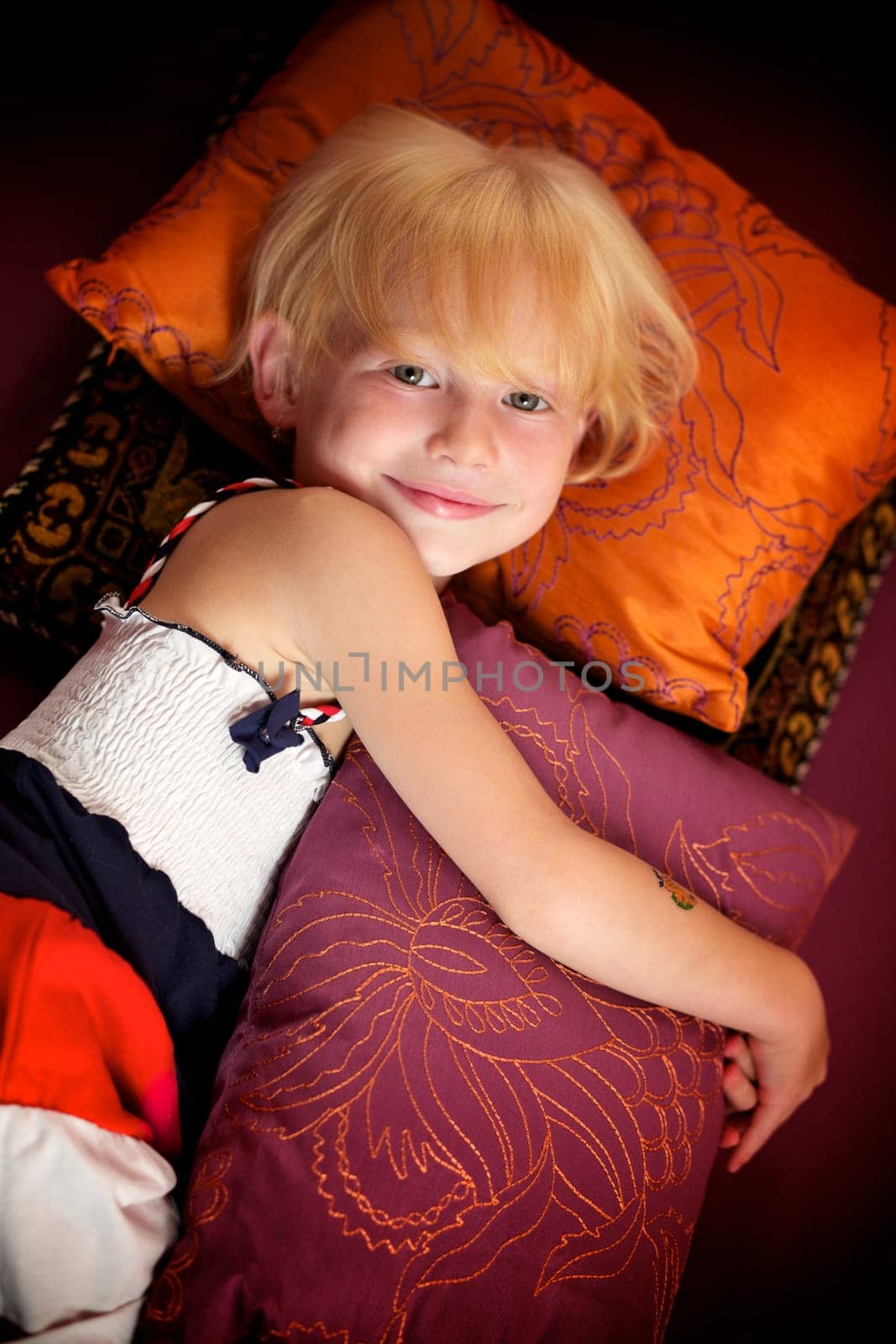 Portrait of a little girl lying among pillows