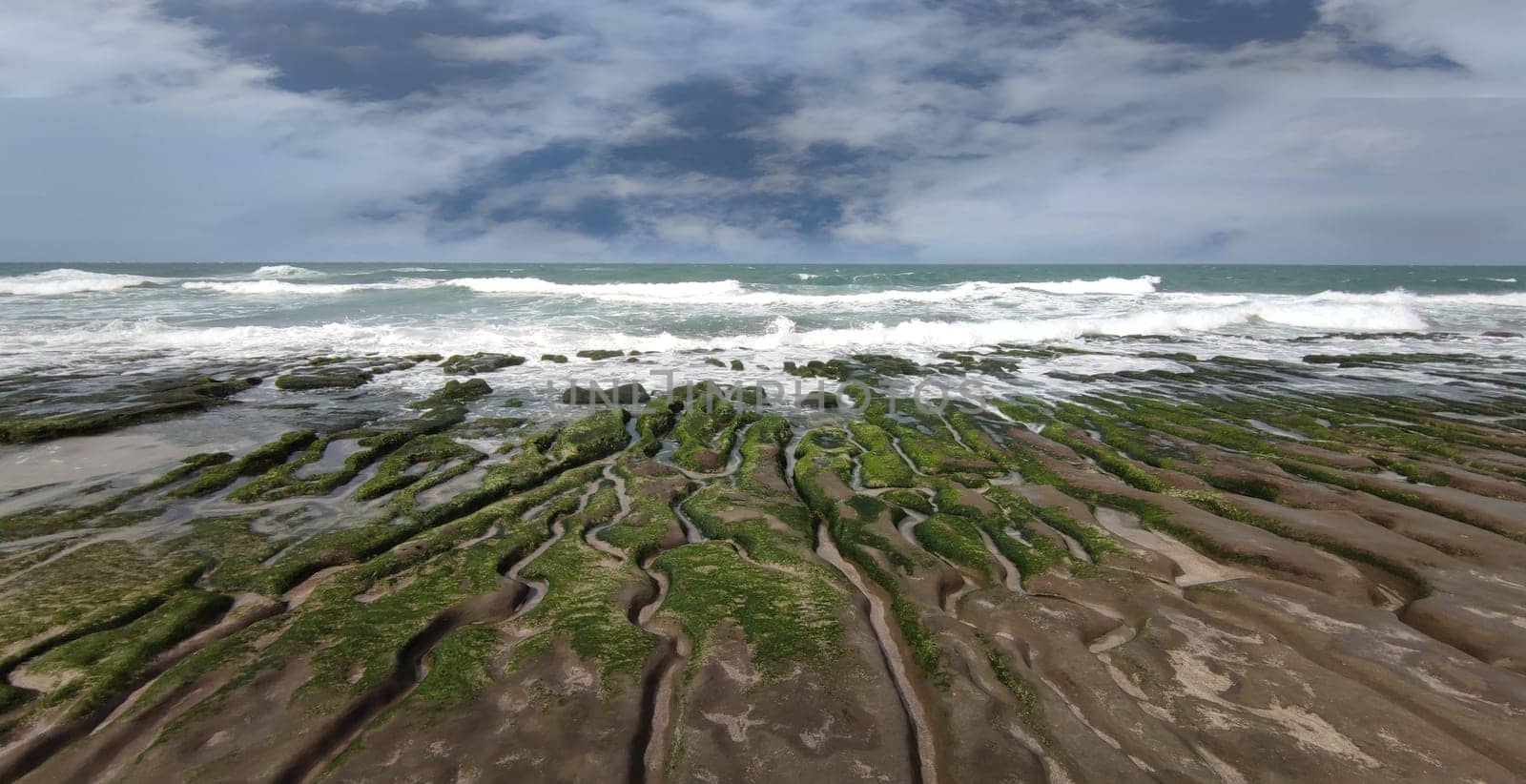The Laomei Green Stone Trough is located in Shimen District on the North Coast, Every April and May, because the northeast monsoon slowly weakens, the local rock trough scientific name: tidal trench and sea erosion trench is covered with a large green seaweed